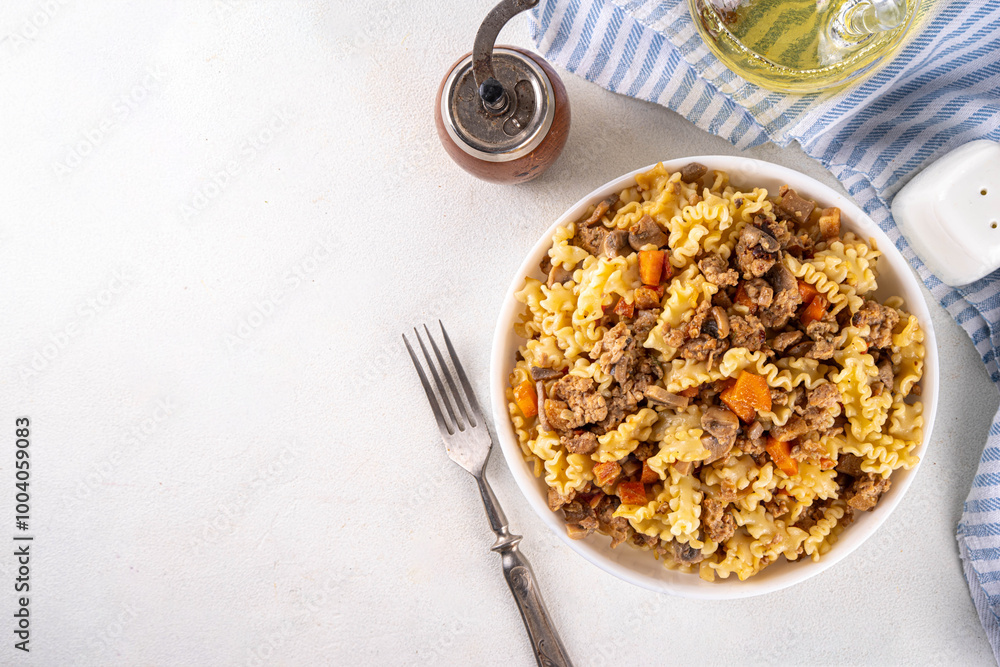 Easy homemade pasta with minced meat. One pot pasta with ground beef and autumn vegetables, in portioned plate on kitchen table Easy homemade pasta with minced meat. One pot pasta with ground beef and autumn vegetables, in portioned plate on kitchen table