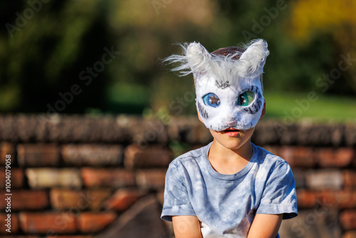 Cute young little kid girl wear cat furry mask enjoy have fun playing outdoors in forest street park. Children therian wild animal character trendy fan culture. Teenager social expression hobby photo