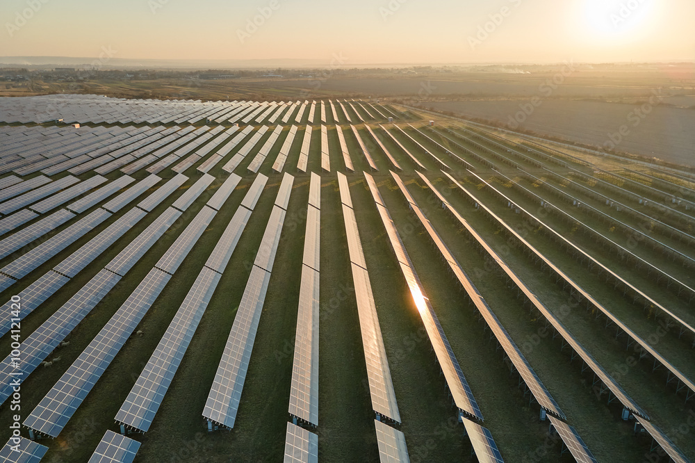 Aerial view of big sustainable electric power plant with many rows of solar photovoltaic panels for producing clean electrical energy at sunset. Renewable electricity with zero emission concept Aerial view of big sustainable electric power plant with many rows of solar photovoltaic panels for producing clean electrical energy at sunset. Renewable electricity with zero emission concept