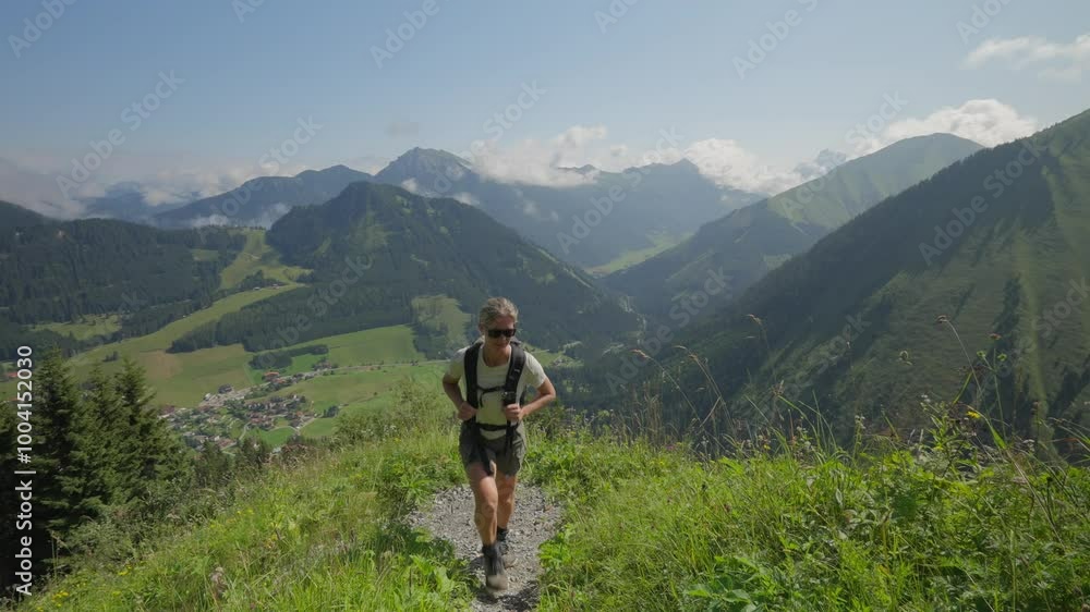 Woman hiking on a mountain trail overlooking green valleys and villages in the Austrian Alps Woman hiking on a mountain trail overlooking green valleys and villages in the Austrian Alps