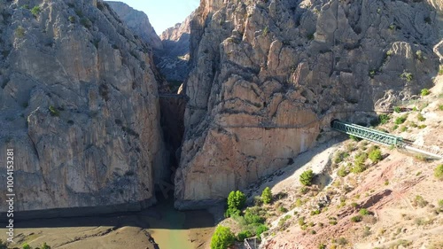 Aerial view from drone to the gorge Garganta del Chorro and Caminito del Rey, Spain. A bridge in a narrow gorge between huge high mountains and a river flows below. Railway bridge.