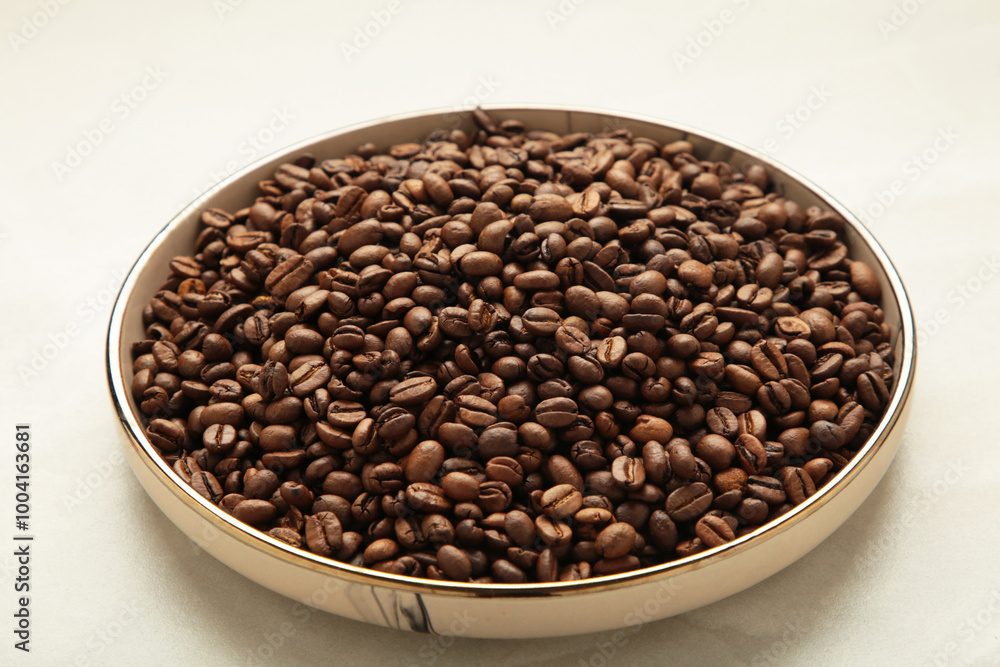 Fototapeta premium Coffee beans on plate on light background