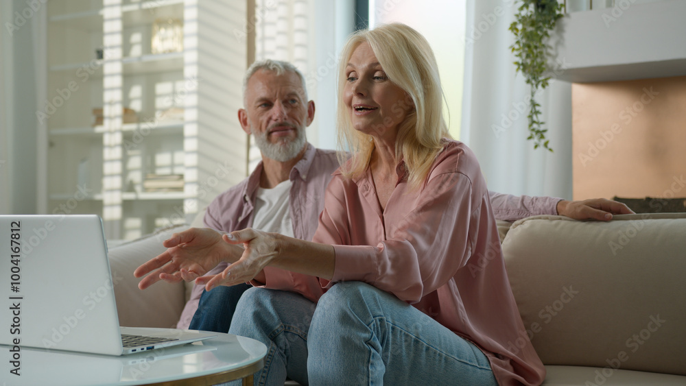 Fototapeta premium Happy satisfied Caucasian married couple grandfather grandmother man woman talking on video call using laptop at home couch online meeting with relatives communicate via computer webcam family support