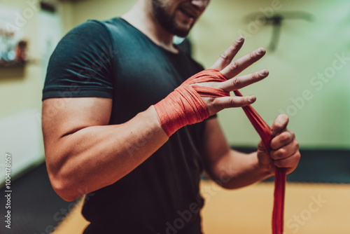 A male hand of boxer or fighter with red boxing bandages before the fight or training in sport gym. photo