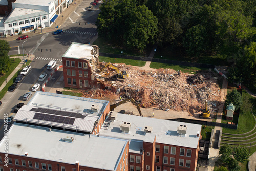 Old building demolition site. Construction excavator tearing down obsolete brick walls. City planning concept photo