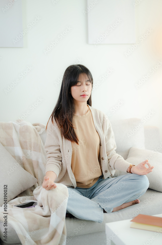 An Asian woman meditating on a sofa. An Asian woman meditating on a sofa.