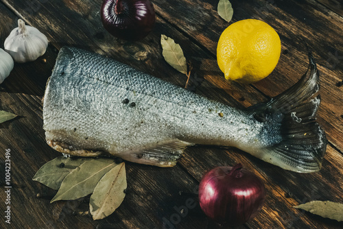 Grilled fish with vegetables (lemon, garlic, onion) on the wooden background