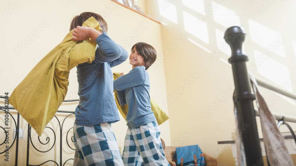 Obraz premium Two young boys play a pillow fight in their parents' bedroom.