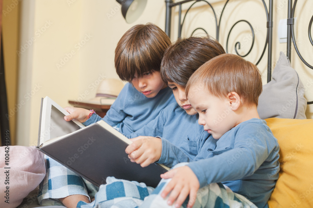 Children reading a storybook together on the bed Children reading a storybook together on the bed