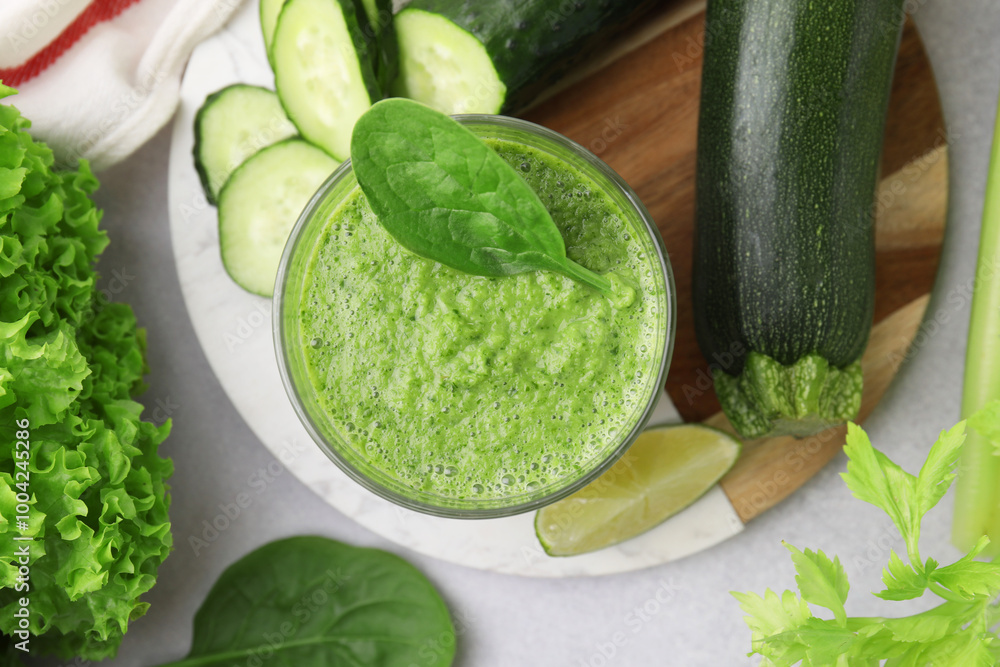 Tasty green smoothie in glass, lime and vegetables on light table, flat lay Tasty green smoothie in glass, lime and vegetables on light table, flat lay