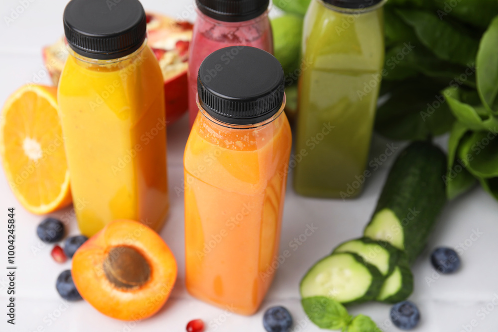 Glass bottles of tasty smoothies and different products on white tiled table, closeup Glass bottles of tasty smoothies and different products on white tiled table, closeup