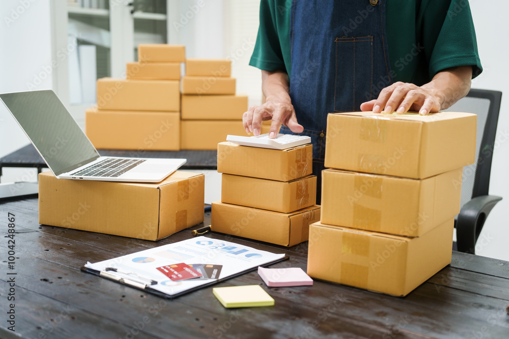 A man is working at his desk, preparing parcel boxes for shipment. He checks and packs items carefully, using shockproof materials, and attaches labels before sending them to customers via EMS. A man is working at his desk, preparing parcel boxes for shipment. He checks and packs items carefully, using shockproof materials, and attaches labels before sending them to customers via EMS.