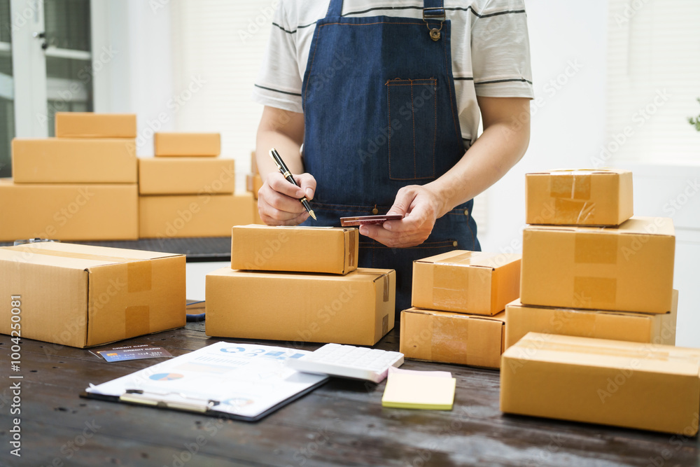 A man is working at his desk, preparing parcel boxes for shipment. He checks and packs items carefully, using shockproof materials, and attaches labels before sending them to customers via EMS. A man is working at his desk, preparing parcel boxes for shipment. He checks and packs items carefully, using shockproof materials, and attaches labels before sending them to customers via EMS.