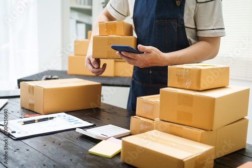 A man is working at his desk, preparing parcel boxes for shipment. He checks and packs items carefully, using shockproof materials, and attaches labels before sending them to customers via EMS. photo