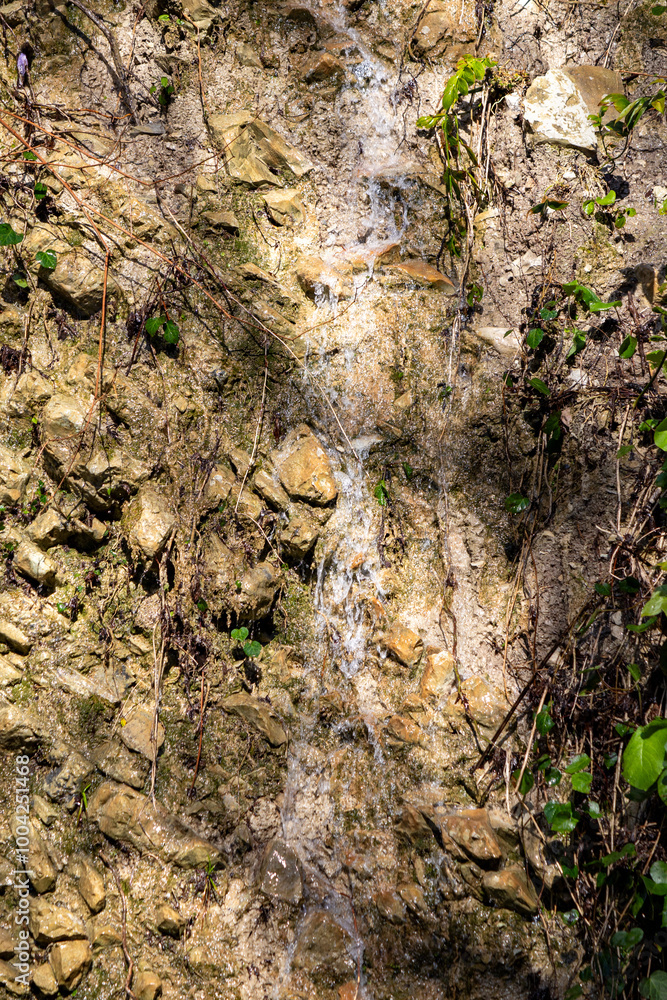 A rock wall with a small stream of water running down it A rock wall with a small stream of water running down it