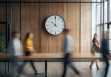 Office environment with people walking past a clock on the wall
