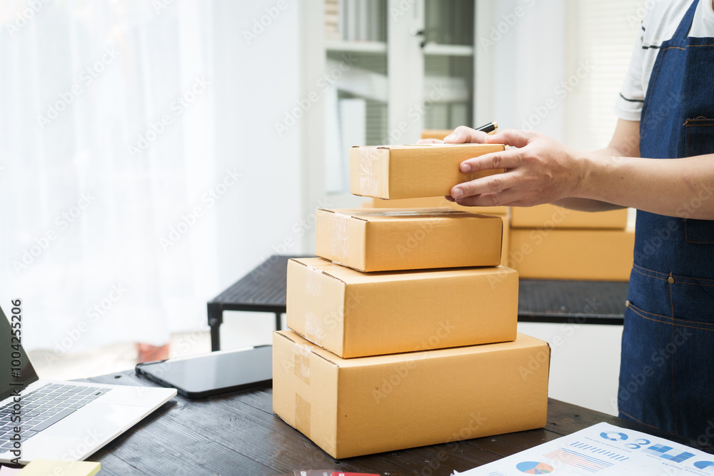 A man is working at his desk, preparing parcel boxes for shipment. He checks and packs items carefully, using shockproof materials, and attaches labels before sending them to customers via EMS. A man is working at his desk, preparing parcel boxes for shipment. He checks and packs items carefully, using shockproof materials, and attaches labels before sending them to customers via EMS.
