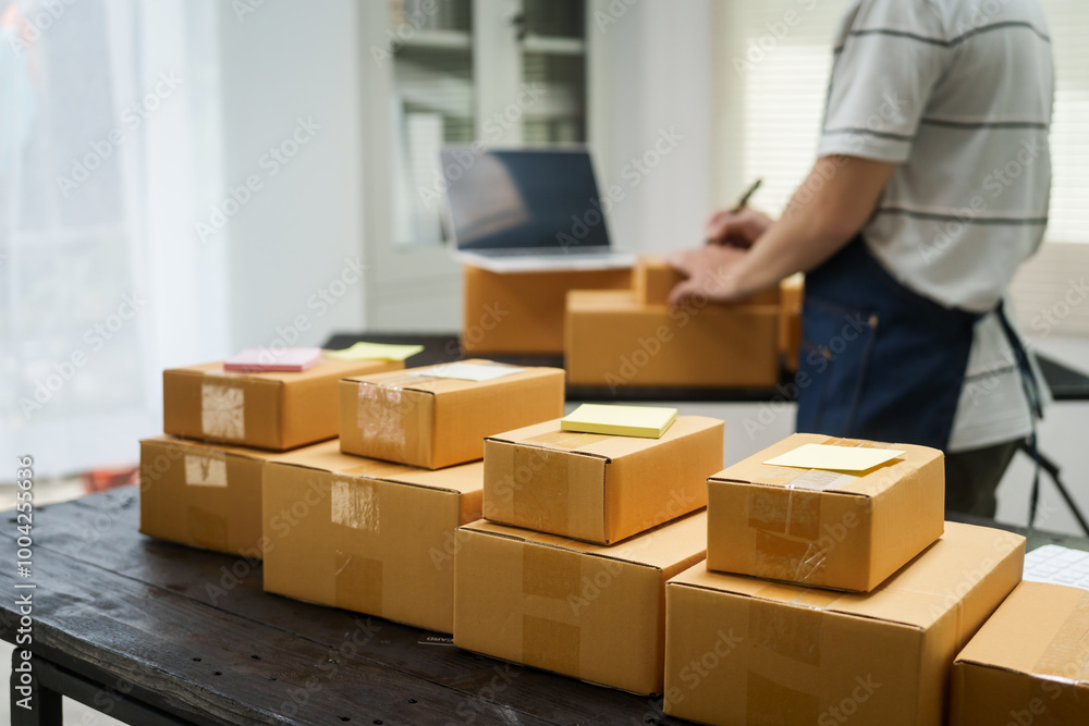 A man is working at his desk, preparing parcel boxes for shipment. He checks and packs items carefully, using shockproof materials, and attaches labels before sending them to customers via EMS. A man is working at his desk, preparing parcel boxes for shipment. He checks and packs items carefully, using shockproof materials, and attaches labels before sending them to customers via EMS.