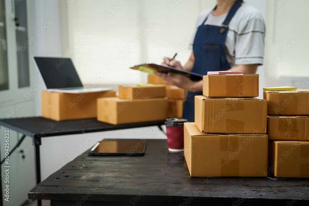A man is working at his desk, preparing parcel boxes for shipment. He checks and packs items carefully, using shockproof materials, and attaches labels before sending them to customers via EMS. A man is working at his desk, preparing parcel boxes for shipment. He checks and packs items carefully, using shockproof materials, and attaches labels before sending them to customers via EMS.