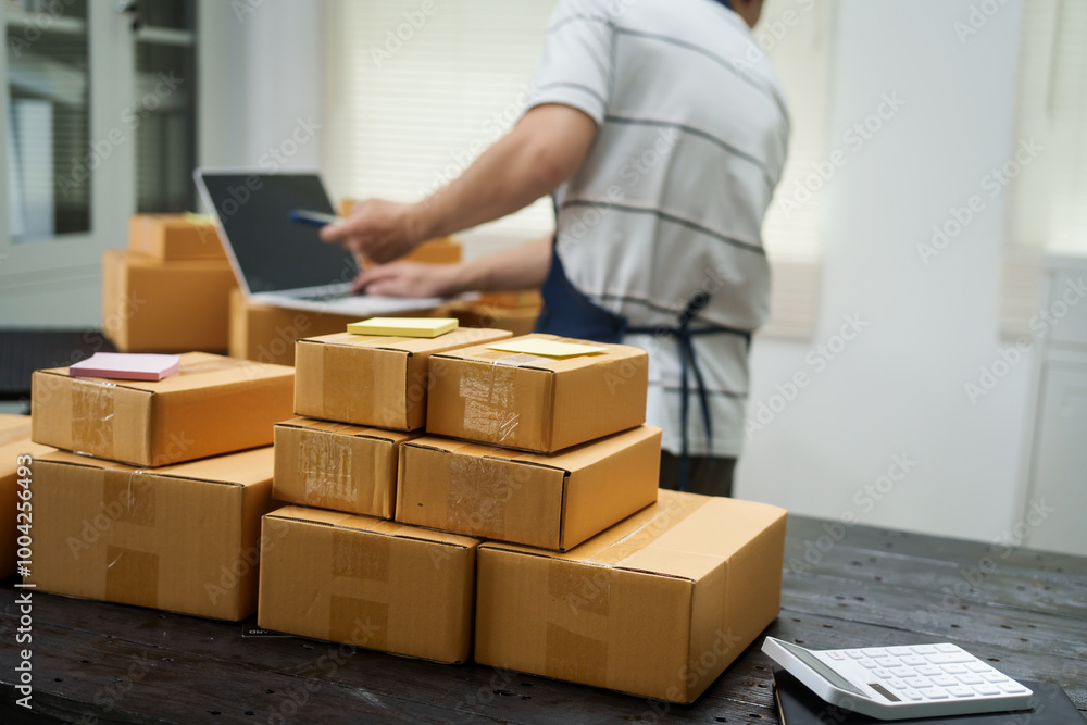 A man is working at his desk, preparing parcel boxes for shipment. He checks and packs items carefully, using shockproof materials, and attaches labels before sending them to customers via EMS. A man is working at his desk, preparing parcel boxes for shipment. He checks and packs items carefully, using shockproof materials, and attaches labels before sending them to customers via EMS.