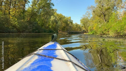 Sailing in a kayak through thesail along a narrow beautiful autumn canal in Dnipro. dense forest on the shore and blue sky. POV kayak