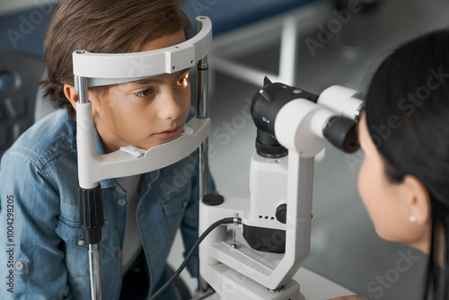 Female doctor ophthalmologist doing basic eye examination of cute boy in modern clinic