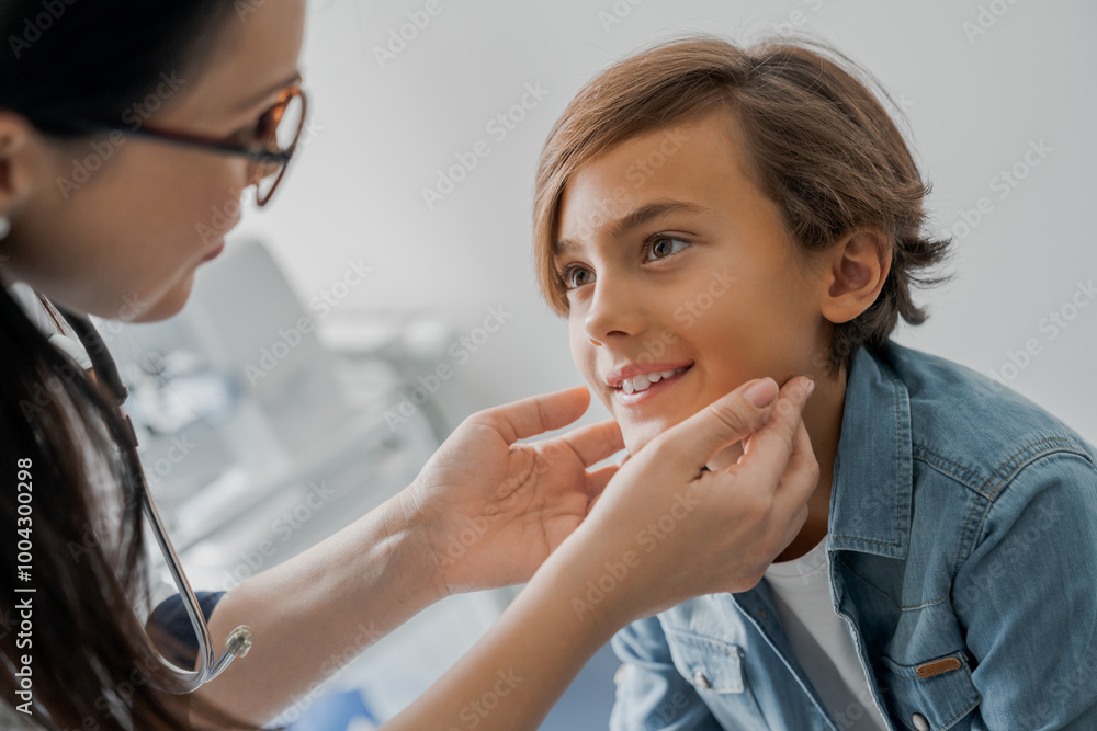 Close up female pediatrician examining gland of little boy in medical clinic Close up female pediatrician examining gland of little boy in medical clinic