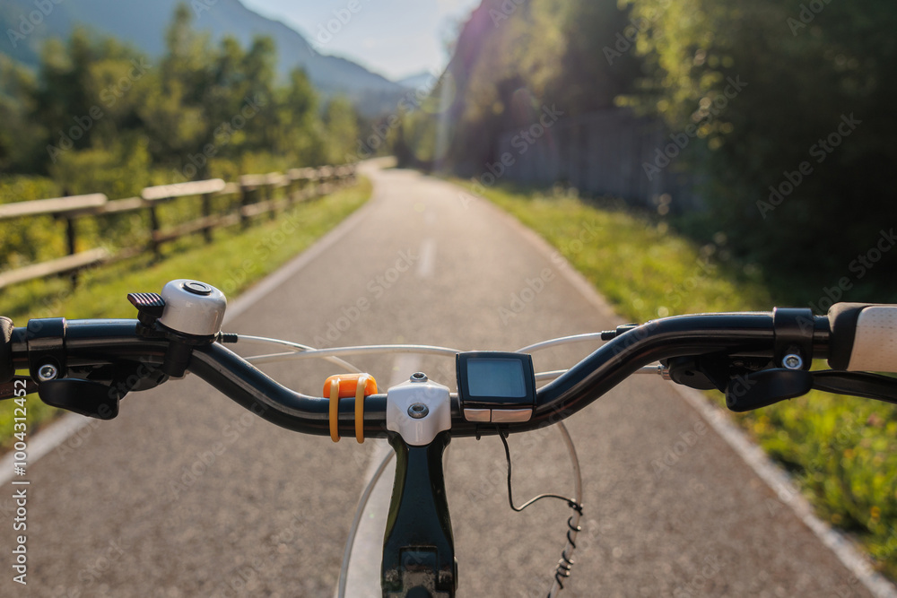 guidando una bicicletta, di giorno, in estate, su una pista ciclabile nel nord Italia. inquadratura con punto di vista che guarda in prospettiva dal manubrio di una bicicletta verso la strada
