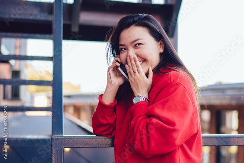 Cheerful female teenager enjoying friendly smartphone conversation for intriguer gossiping and rumors, happy chinese hipster girl making international smartphone conversation connected to roaming