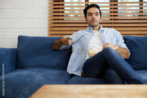 young handsome man watching movies and eating popcorn in a living room