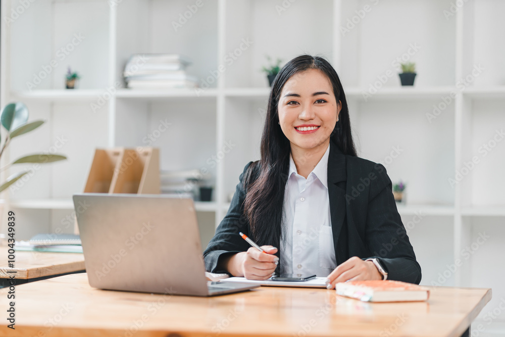 confident businesswoman smiles while working at her desk, showcasing modern office environment. She is engaged with her laptop and notes, reflecting professionalism and productivity. confident businesswoman smiles while working at her desk, showcasing modern office environment. She is engaged with her laptop and notes, reflecting professionalism and productivity.