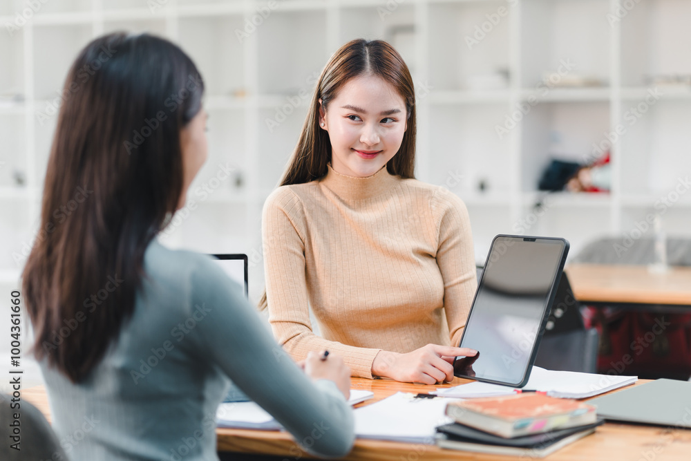 Collaborative discussion between two women in modern workspace, showcasing engagement and teamwork. atmosphere is productive and focused, highlighting use of technology. Collaborative discussion between two women in modern workspace, showcasing engagement and teamwork. atmosphere is productive and focused, highlighting use of technology.
