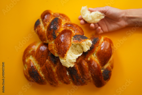 fresh homemade challah bread on a bright background, a piece of bread in the hand photo