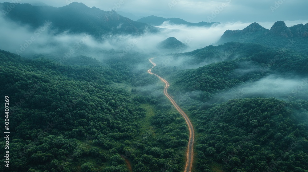 Fototapeta premium Serene landscape with winding road through misty mountains.