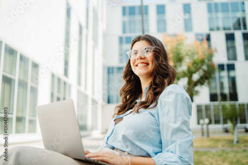 Free Download Young businesswoman is working on laptop in front of modern building	 - GFXLoad