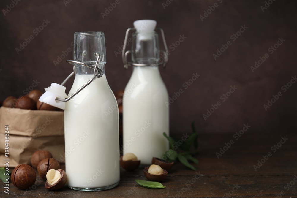 Bottles of macadamia milk and nuts on wooden table. Space for text Bottles of macadamia milk and nuts on wooden table. Space for text