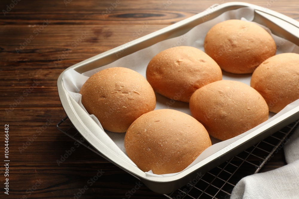 Fresh tasty buns in baking tray on wooden table, closeup Fresh tasty buns in baking tray on wooden table, closeup