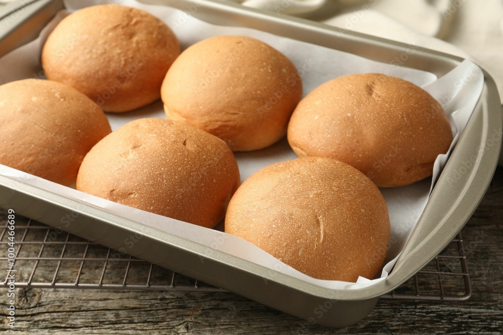 Fresh tasty buns in baking dish on wooden table, closeup Fresh tasty buns in baking dish on wooden table, closeup