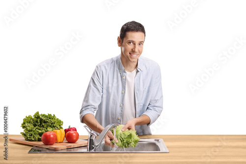 Young man washing vegetables in a sink and smiling