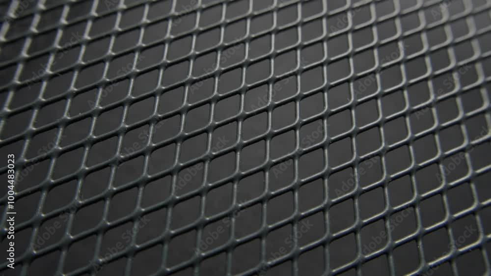 A detailed close-up of a metal grid with a black background, highlighting the geometric pattern of the mesh. A detailed close-up of a metal grid with a black background, highlighting the geometric pattern of the mesh.
