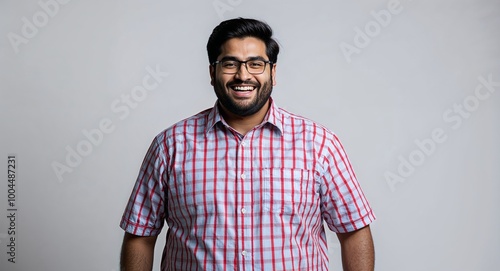 Grinning young Indian man with a fuller figure in studio portrait on clear white background