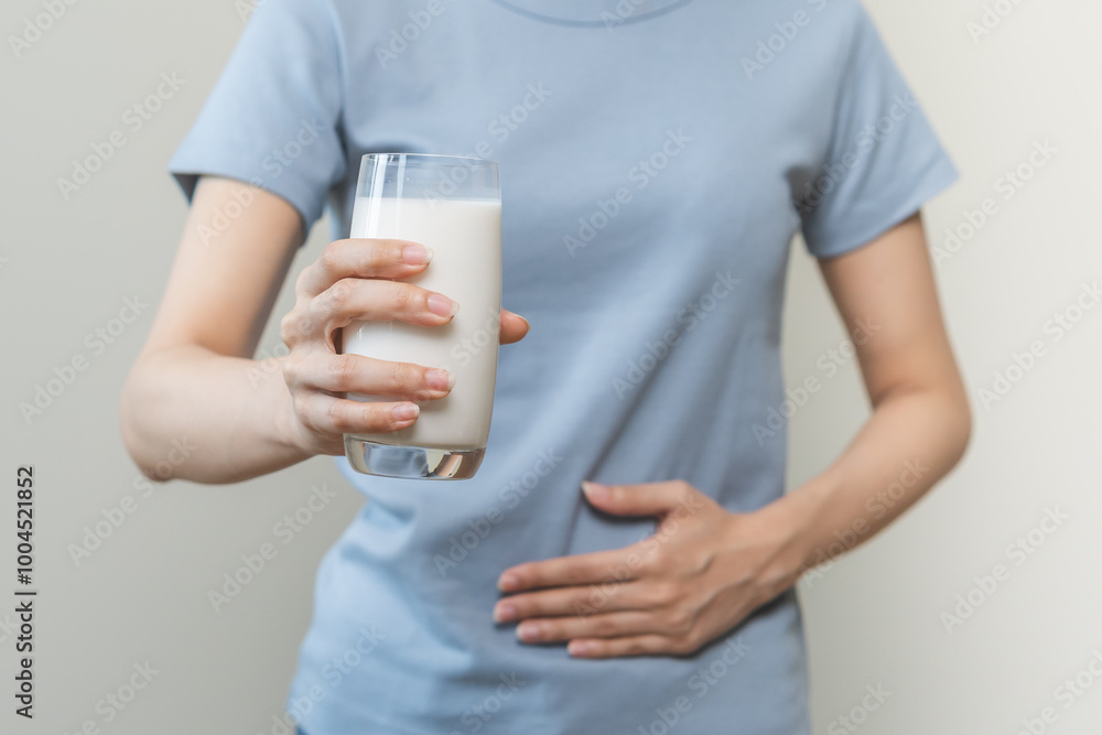 Pain, suffering asian young woman having a stomachache, abdominal pain or digestive, hand in holding belly after drink glass of milk. Lactose intolerance, allergy from dairy food, health care problem. Pain, suffering asian young woman having a stomachache, abdominal pain or digestive, hand in holding belly after drink glass of milk. Lactose intolerance, allergy from dairy food, health care problem.