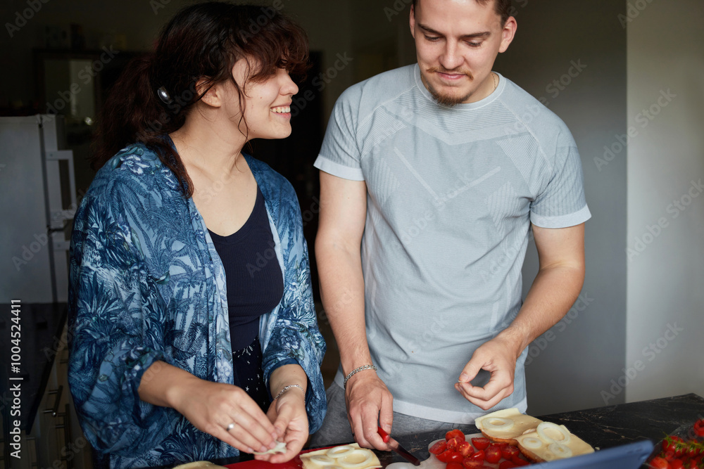 A young couple cooks food together at home using a tablet. A young couple cooks food together at home using a tablet.