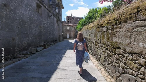 Tourist woman leisurely strolling through the cobbled streets of the medieval town of Tui, Galicia Spain.