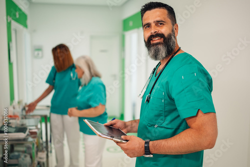 Portrait of a smiling doctor with tablet in hospital corridor with staff. photo