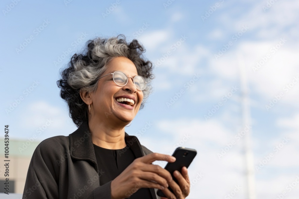 Fototapeta premium Senior indian business woman using smartphone facetiming laughing glasses smile.