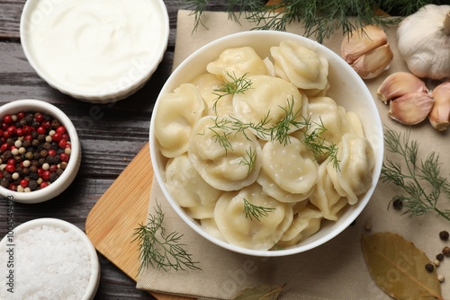 Delicious pelmeni with dill served on wooden table, flat lay photo