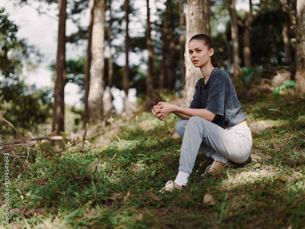Thoughtful young woman sitting on the grass in a forest, wearing casual outfit and sneakers, enjoying nature and reflecting Peaceful and serene atmosphere Thoughtful young woman sitting on the grass in a forest, wearing casual outfit and sneakers, enjoying nature and reflecting Peaceful and serene atmosphere