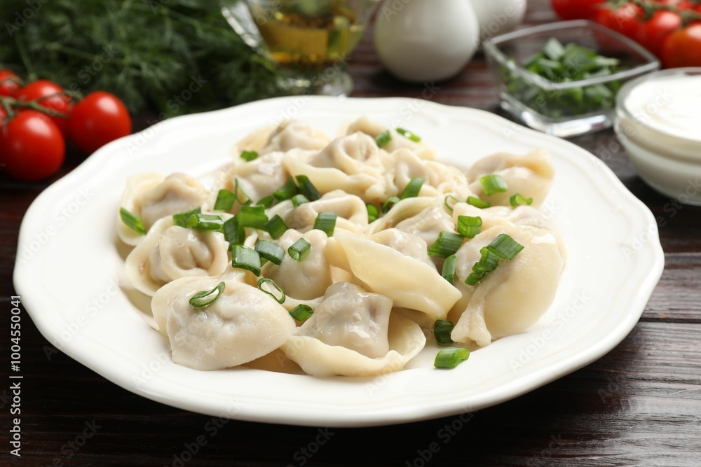Delicious pelmeni with green onion on wooden table, closeup