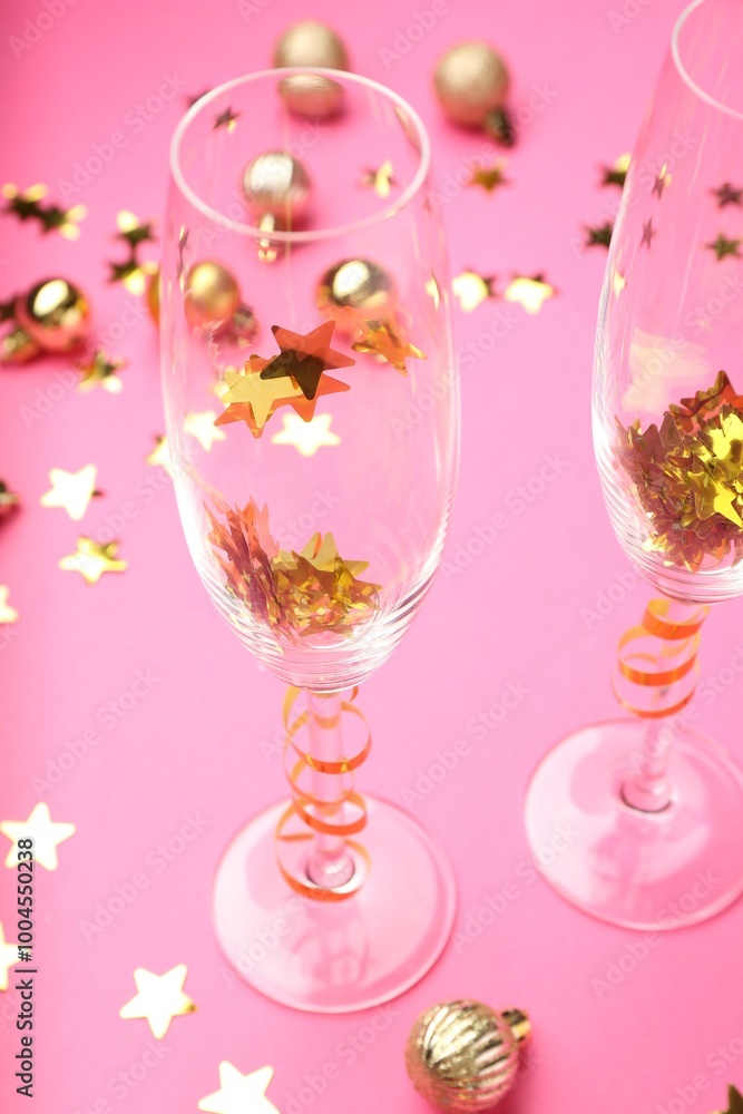 Wine glasses with confetti on pink background, closeup. Christmas decor Wine glasses with confetti on pink background, closeup. Christmas decor